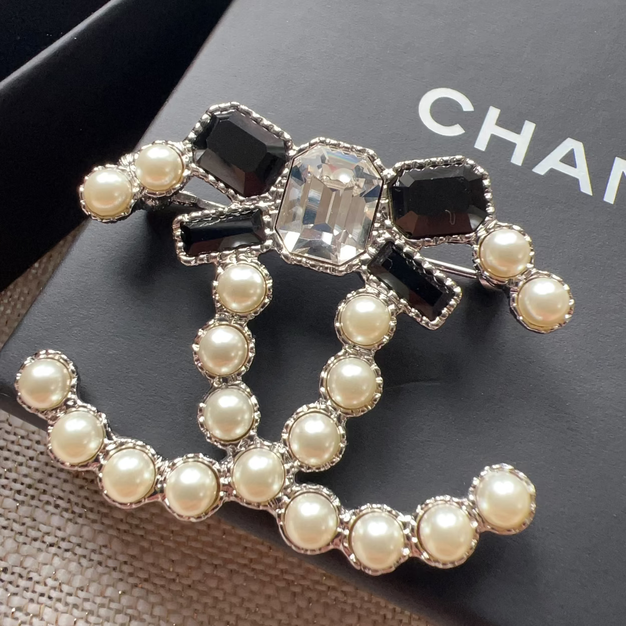 Pearl and black gem brooch on a Chanel box