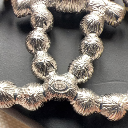 Close-up of a textured silver belt buckle on a dark surface.