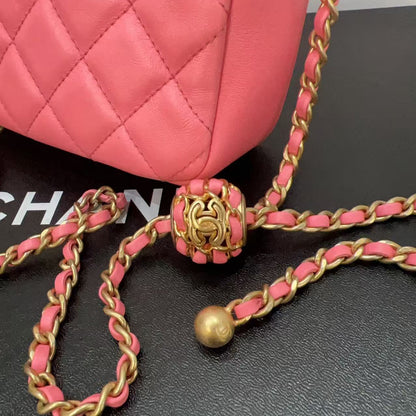 Pink and gold handbag strap on a black surface with a pink quilted handbag in the background.