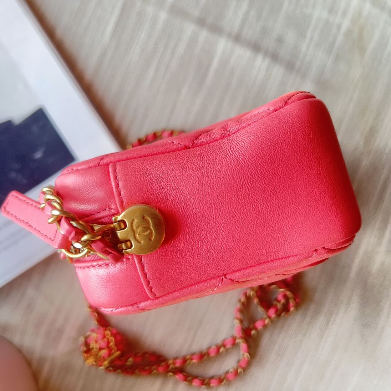 Red handbag with gold chain on a light wooden surface