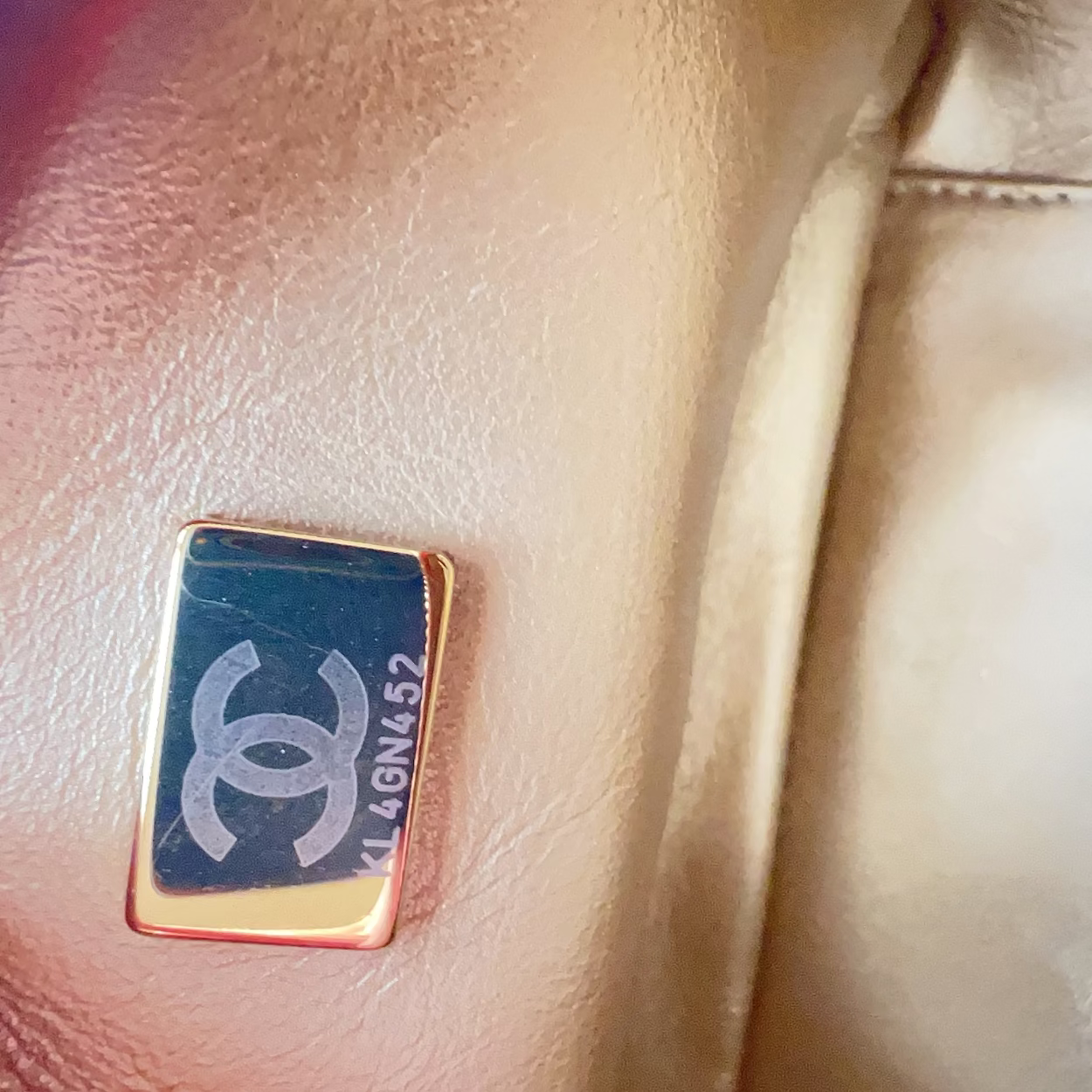 Close-up of a Chanel logo on a beige leather jacket.