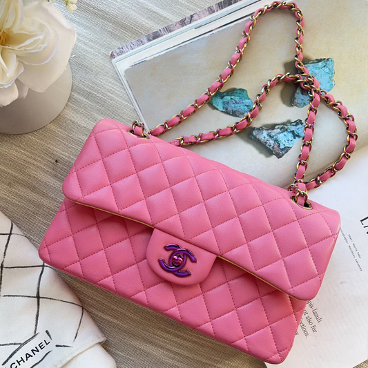 Pink quilted handbag with a brand logo on a wooden surface