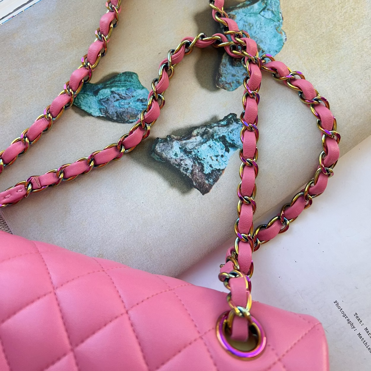 Pink handbag with a chain strap on a textured surface