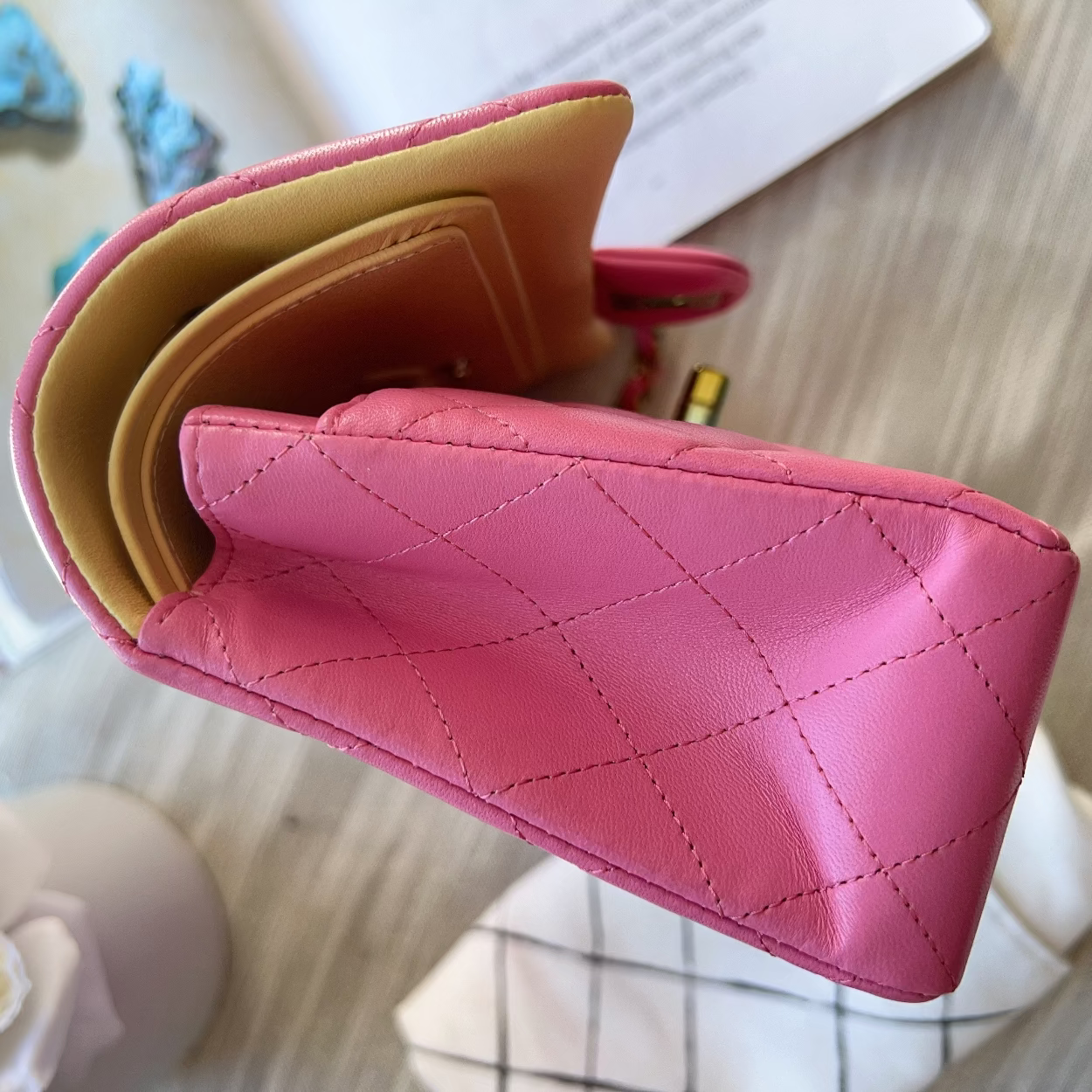 Pink quilted wallet on a light wooden surface with a blurred background