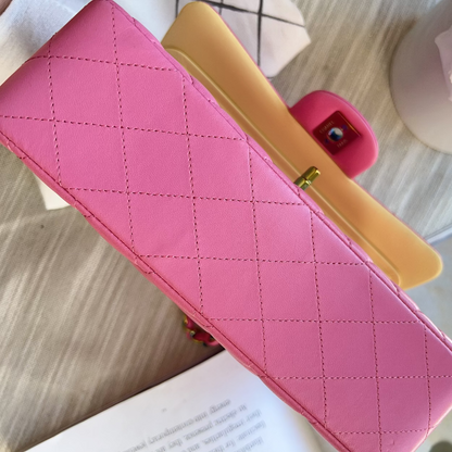 Pink quilted handbag with gold clasp on a light surface