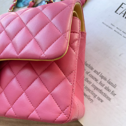 Pink quilted handbag on a textured surface with text partially visible