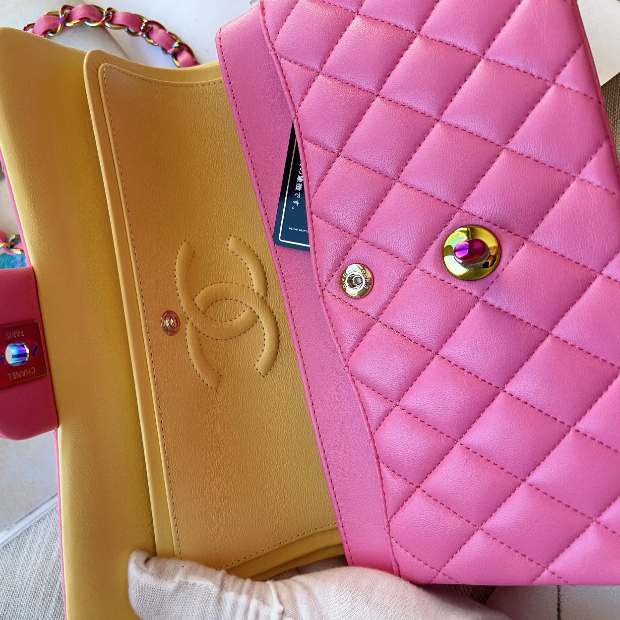Yellow and pink handbags with a visible brand logo on a textured surface.