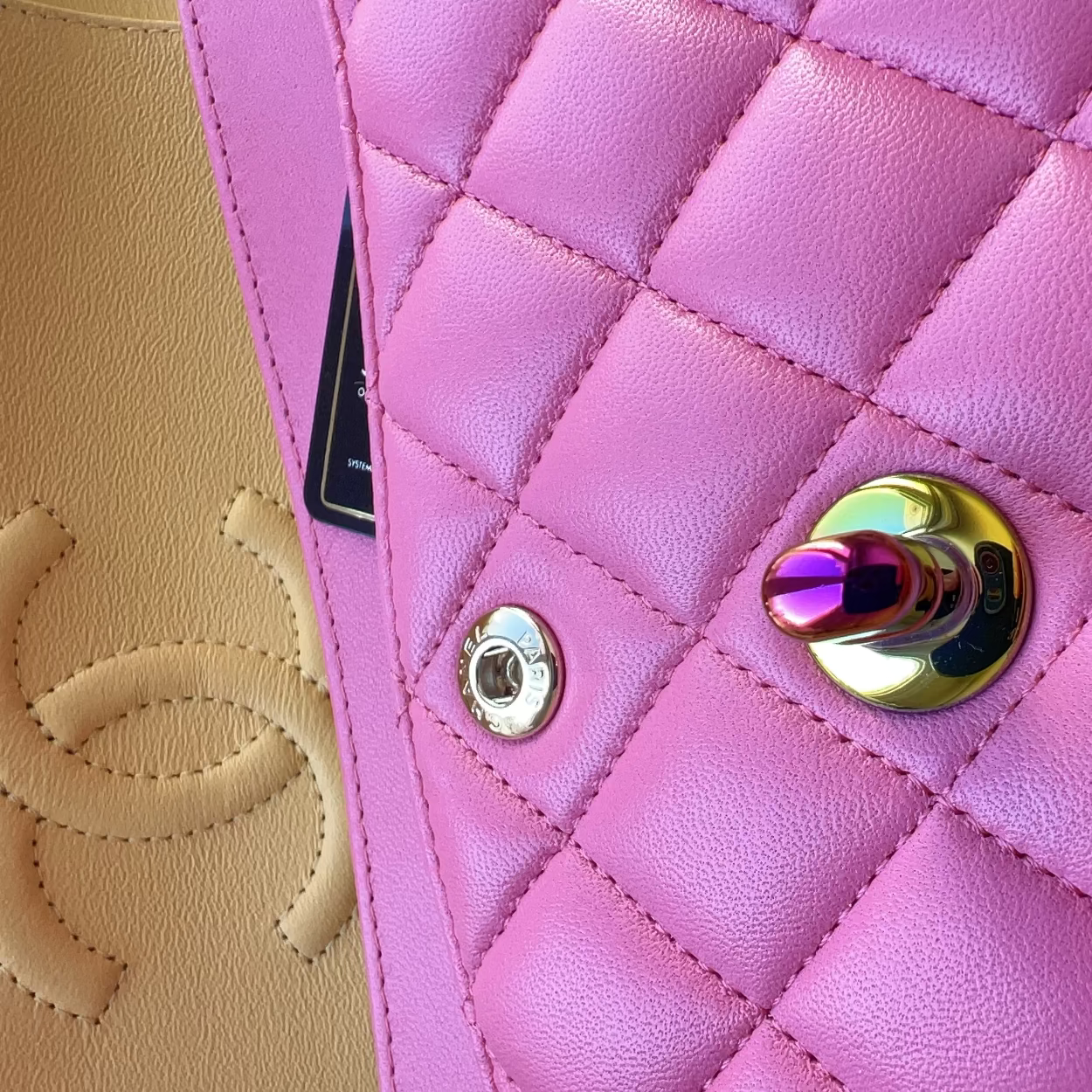 Close-up of a pink quilted handbag with a gold button, blurred beige background