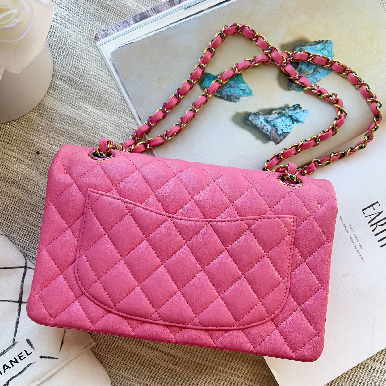 Pink quilted handbag with a colorful strap on a wooden surface