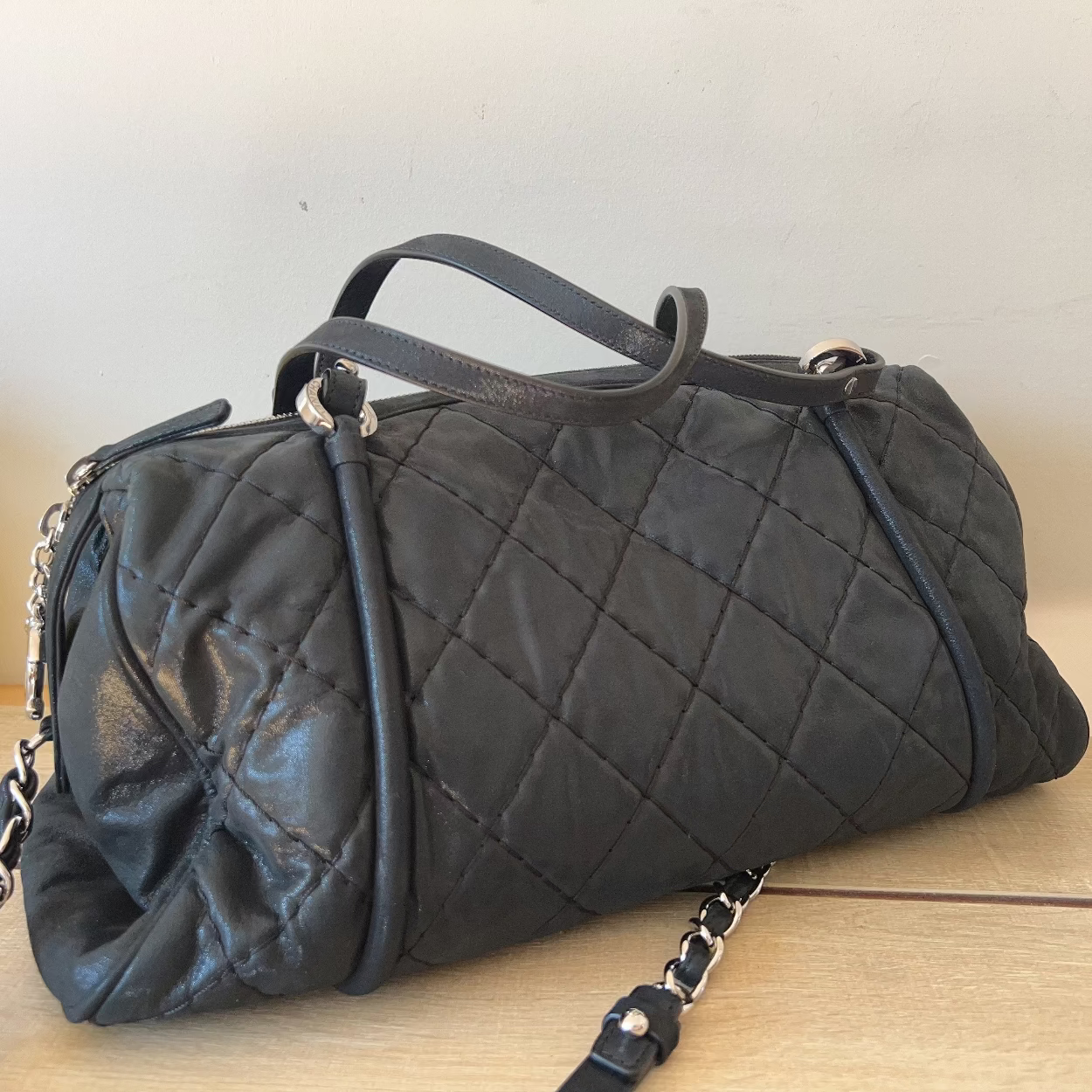 Black quilted handbag on a wooden surface with a white background