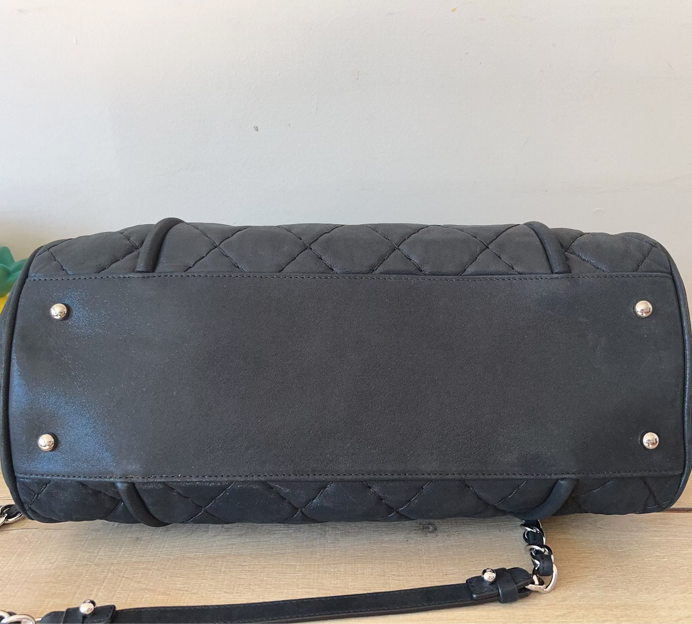 Black quilted handbag with silver studs on a wooden surface