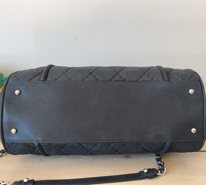 Black quilted handbag with silver studs on a wooden surface