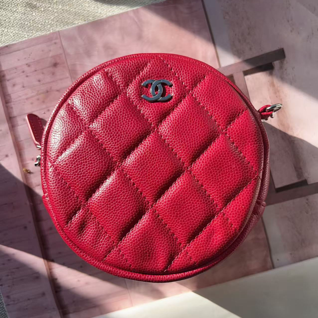 Red quilted Chanel purse on a wooden surface