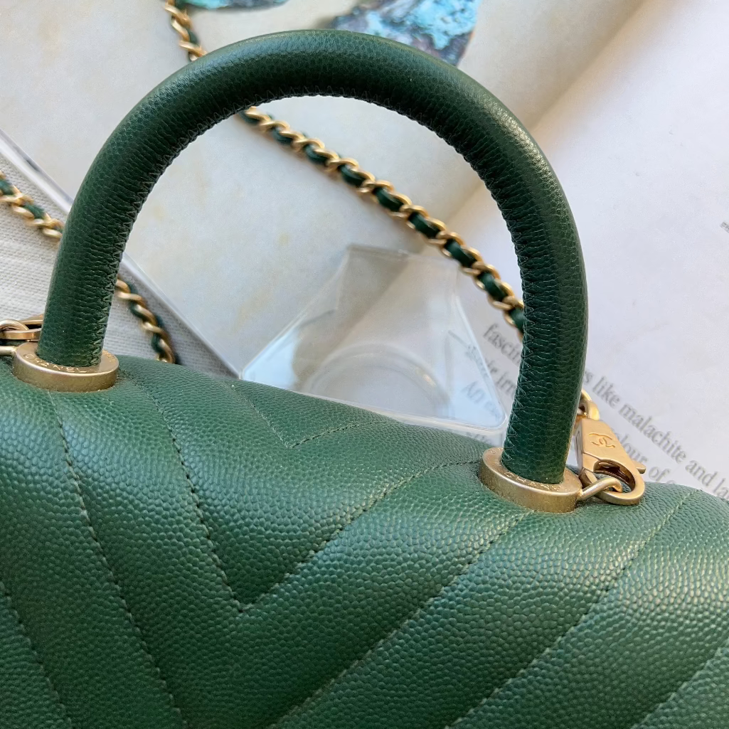Green handbag with gold handle and chain on a magazine background