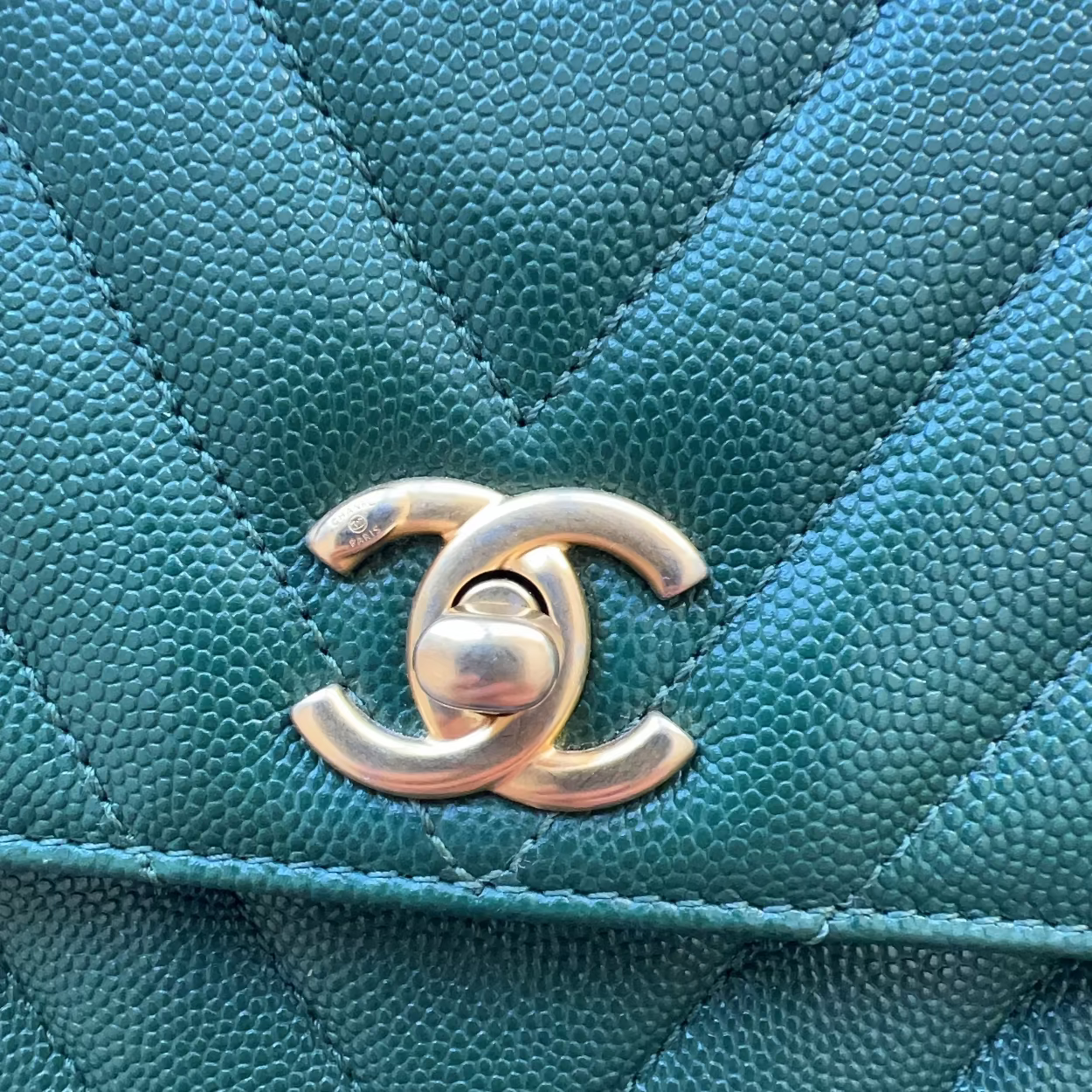 Close-up of a teal quilted handbag with Chanel logo.