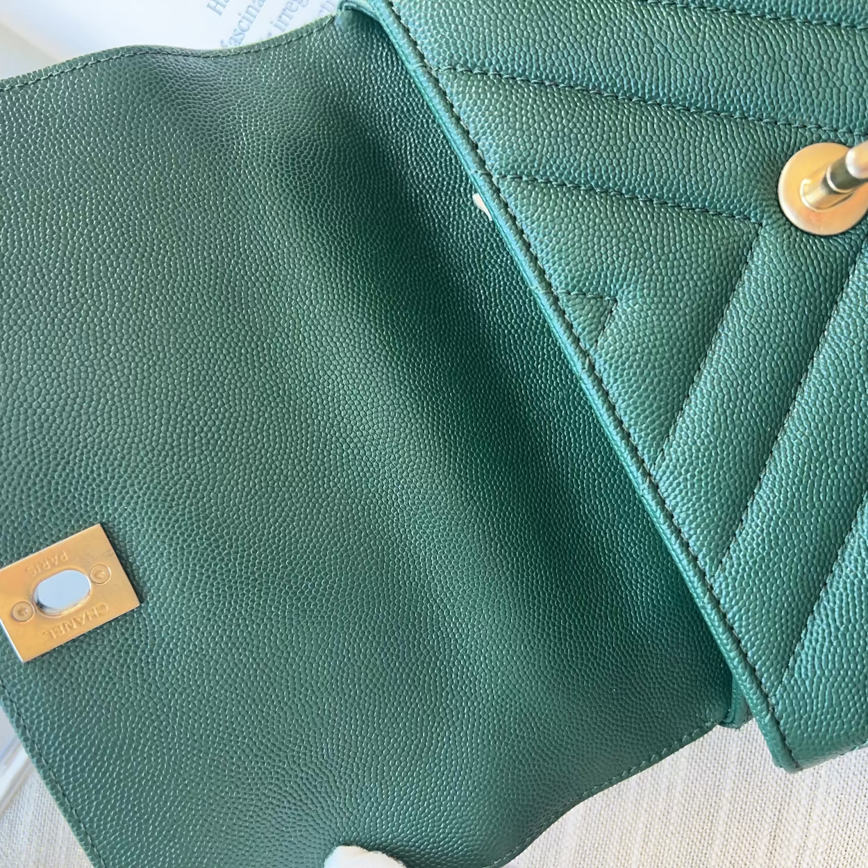 Close-up of a green leather wallet with gold accents on a light wooden surface.