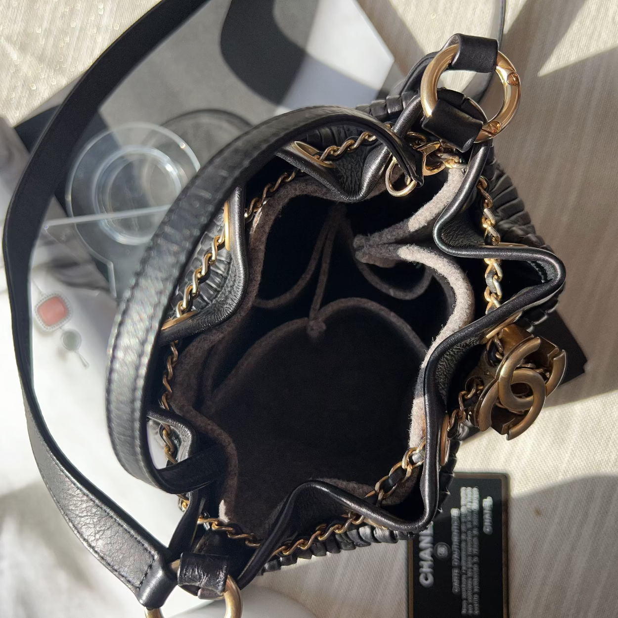 Black handbag with gold chain details on a light wooden surface