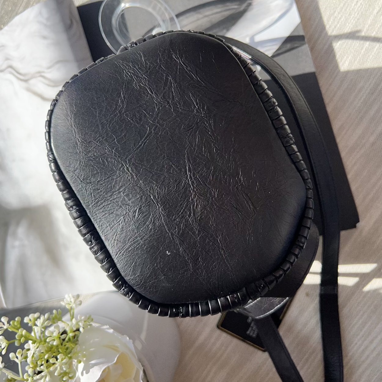 Black leather case on a table with a magazine and flowers in the background