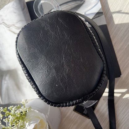 Black leather case on a table with a magazine and flowers in the background