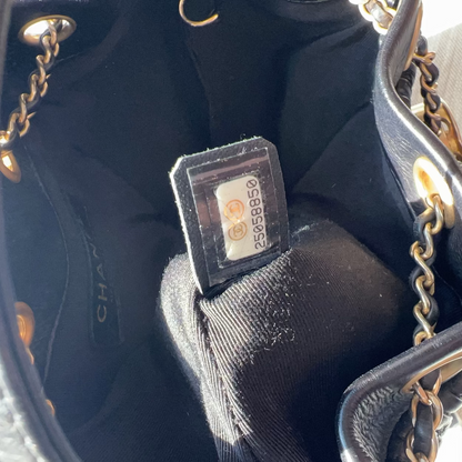 Black handbag with gold chain detail and visible brand logo, held open to show interior.