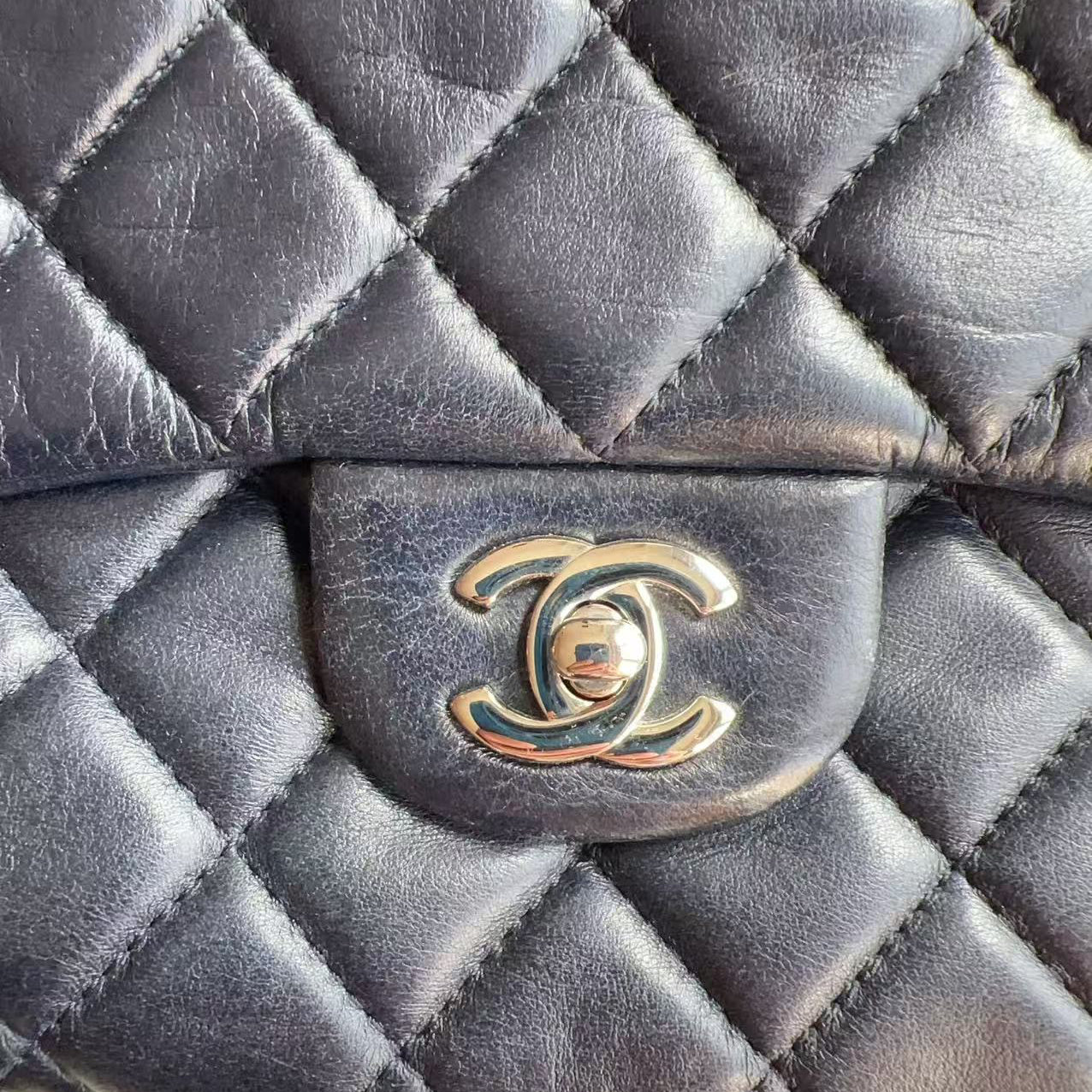 Close-up of a Chanel handbag with quilted design and logo.