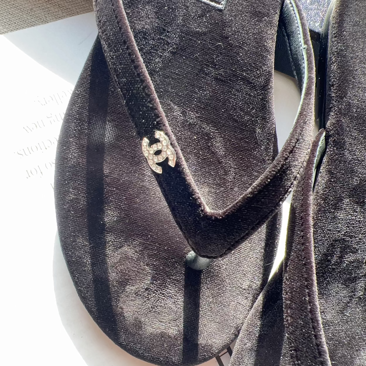 Pair of Chanel sandals on a white surface with a blurred background