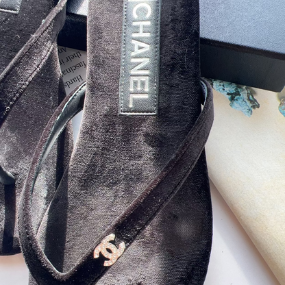 Black Chanel sandal with logo on a white surface