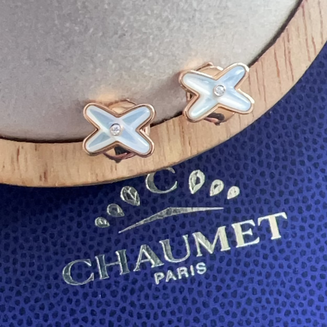 Pair of X-shaped earrings on a Chaumet Paris branded stand.