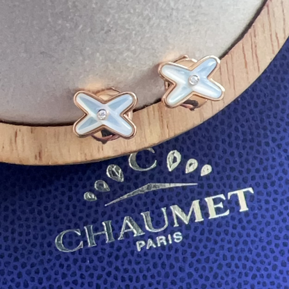 Pair of X-shaped earrings on a Chaumet Paris branded stand.