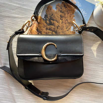Black handbag with gold accents on a wooden surface