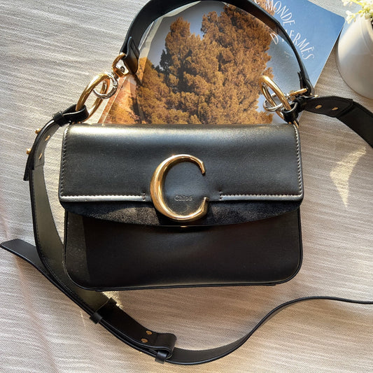Black handbag with gold accents on a wooden surface