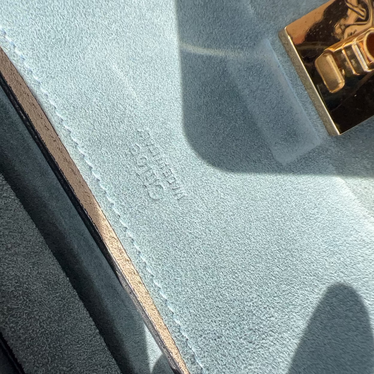 Close-up of a textured surface with a gold lock and visible brand name.