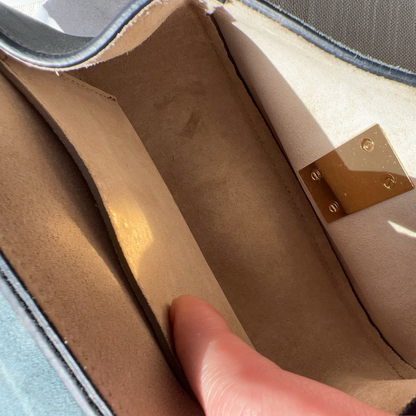 Close-up of a brown leather bag with a gold metal clasp.