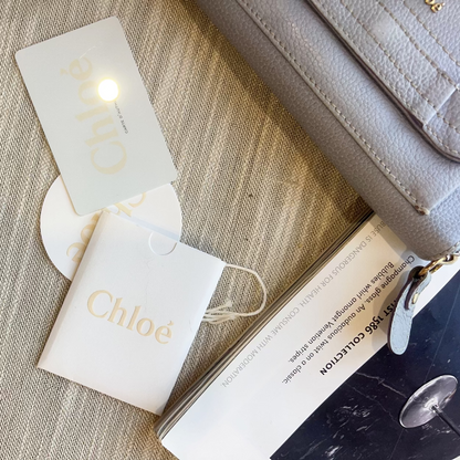 Chloe handbag with branded pouch and card on a textured surface