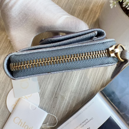 Blue wallet with gold zipper on a wooden surface
