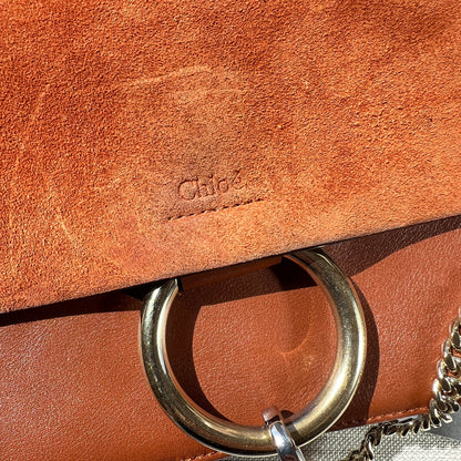 Brown leather bag with a metal ring handle on a light gray background