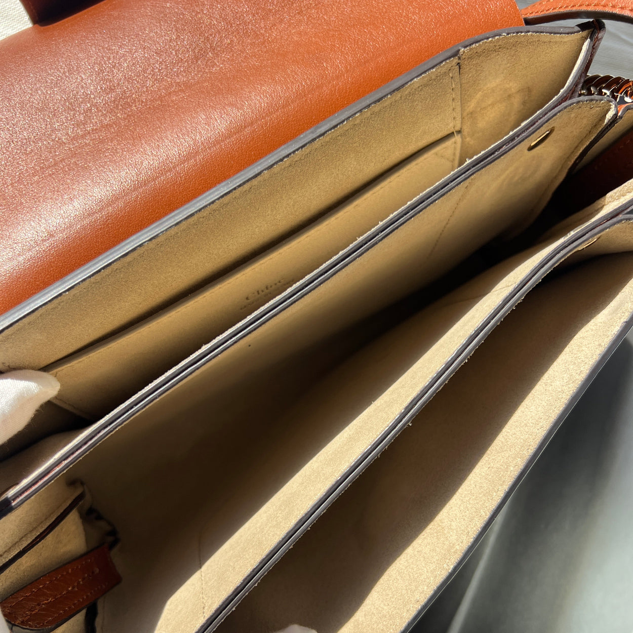 Close-up of a brown leather bag with a zipper, showing the interior.