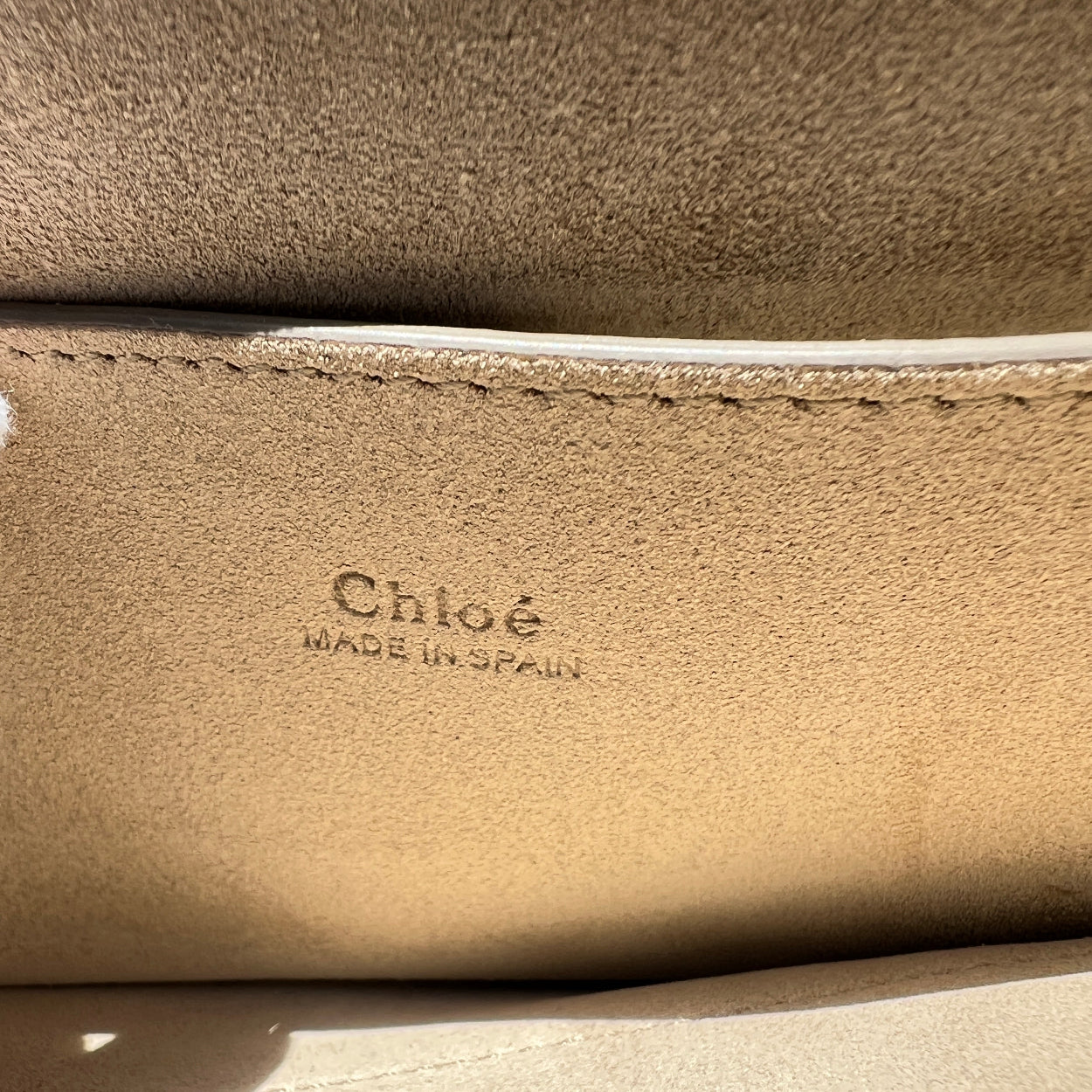 Close-up of a beige leather surface with 'Chloé' branding.
