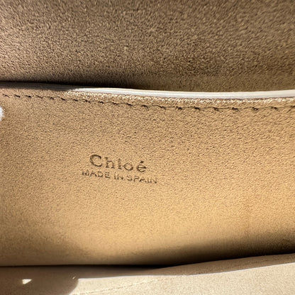 Close-up of a beige leather surface with 'Chloé' branding.