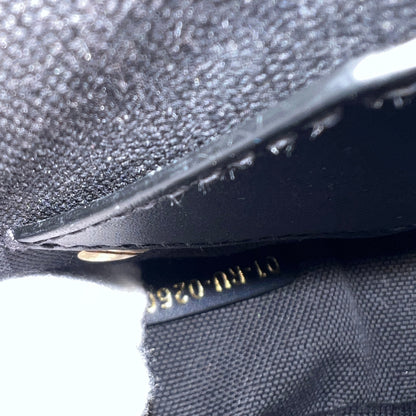 Close-up detail of a black textured fabric item with a black leather trim and gold stamped numbering.
