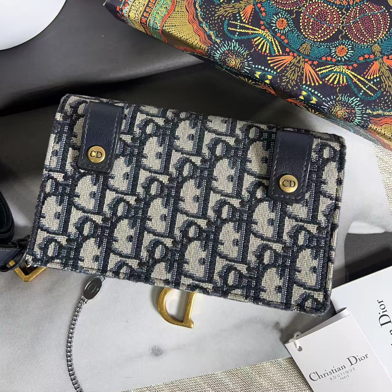 Dior wallet with brand box and tag on a marble surface