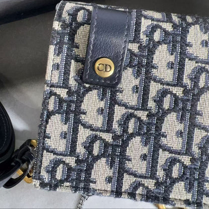 Designer handbag with patterned fabric and gold logo on a textured surface