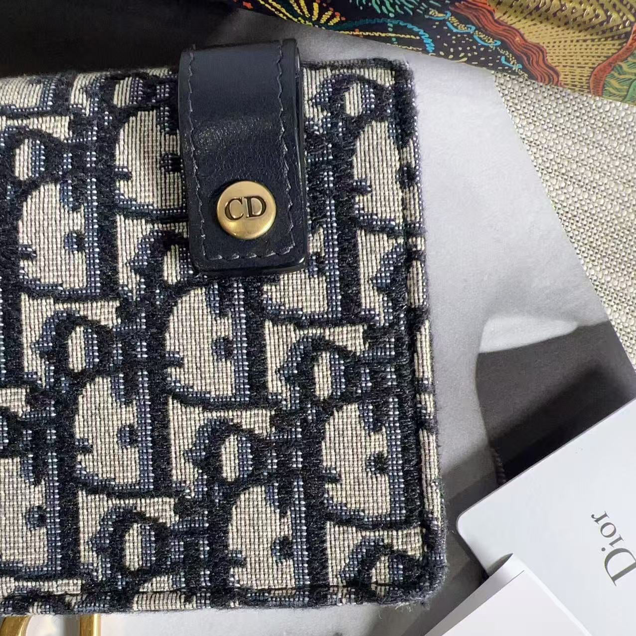 Dior handbag with patterned fabric and gold hardware on a marble surface.