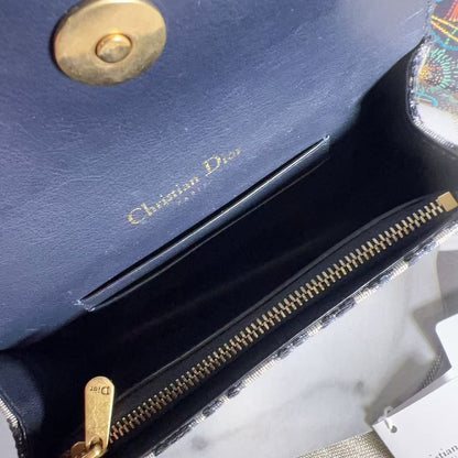Blue Dior handbag with gold zipper and logo, held open by a hand.
