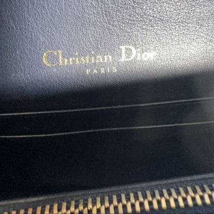 Close-up of a black leather product with 'Christian Dior' branding.