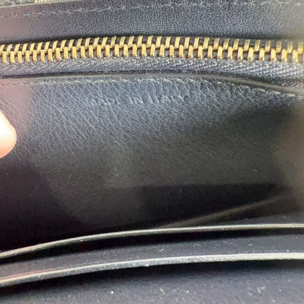 Close-up of a black leather wallet with a gold zipper.