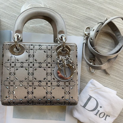 Designer handbag with decorative chain detail on a textured surface with a branded cloth.