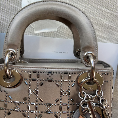 Designer handbag with gold hardware and chain detail on a neutral background