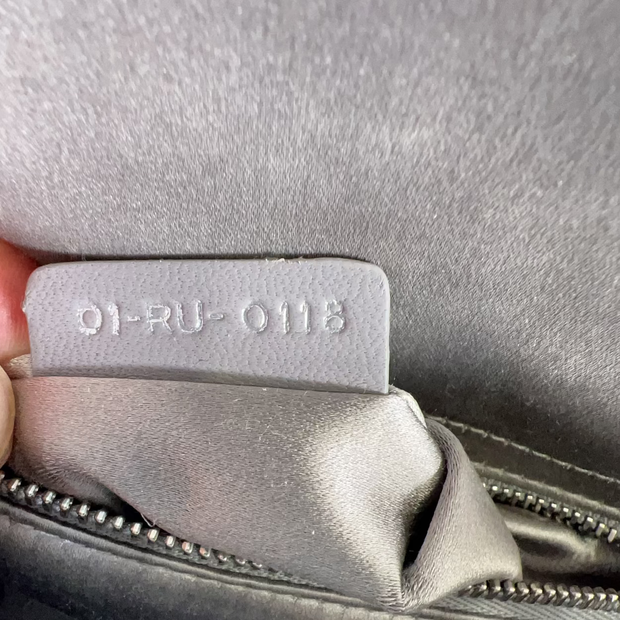 Close-up of a suitcase label with text on a gray suitcase.
