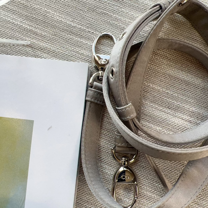 Close-up of a beige handbag with a strap on a textured surface